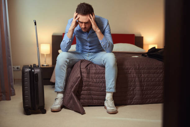 istock Guy with headache sitting on big bed in modern hotel 1509721163