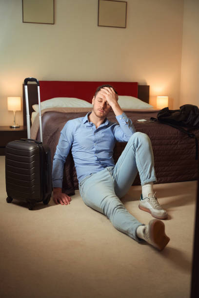 istock Tired guy holding head sitting on bed in hotel room 1509721411