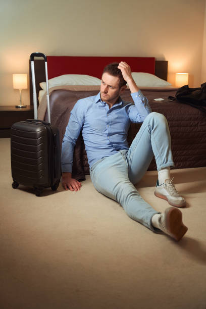 istock Sad young man sits on floor near bed in hotel 1509721437