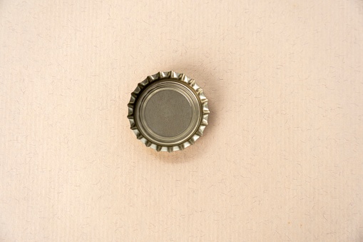 A close-up image of a bottle cap on a pink background