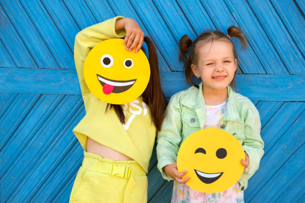 istock Humorous kids hold various smile faces and make faces standing at blue wall 1509763958