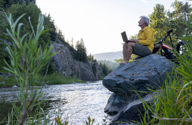 istock Man uses laptop on rock above stream 1509835667