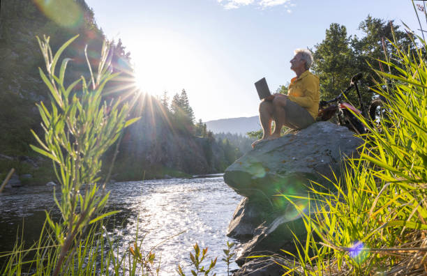 istock Man uses laptop on rock above stream 1509835668