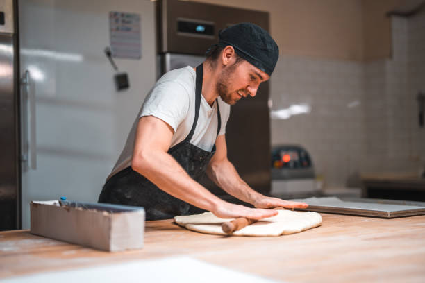 istock Caucasian Male Baker Using A Rolling Pin In A Bakery 1509988490