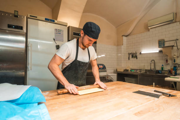 istock Caucasian Male Baker Using A Rolling Pin In A Bakery 1509988515