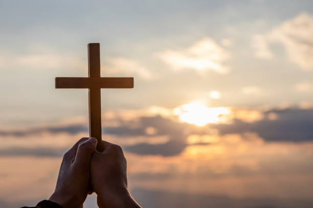 istock Christian, Christianity, Religion copy space background. Silhouette hands praying and holding christian cross for worshipping God at sunset background. 1509999746
