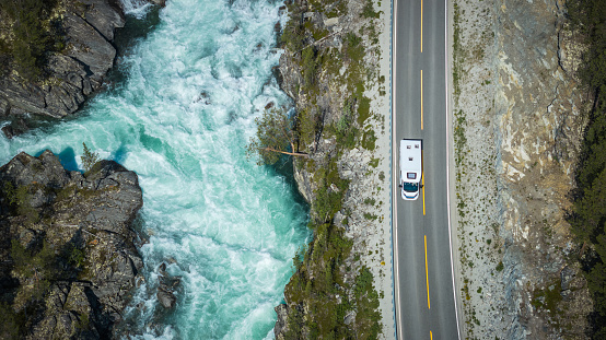Aerial View of a Modern Camper Van RV on the Scenic Norwegian Road Next to Mountain River