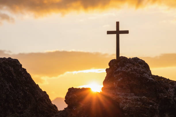 silhouettes of crucifix symbol on top mountain with bright sunbeam on the colorful sky background - summit cross imagens e fotografias de stock