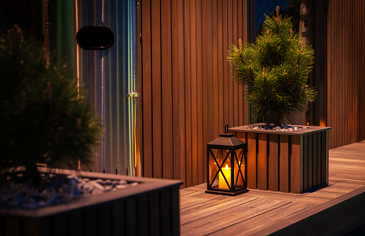 Modern Residential Garden Decorative Elements. Composite Made Garden Shed and a Pot. Evening Time Illumination.