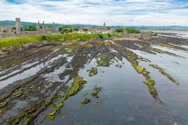 Drone view of St. Andrews, Fife Scotland with rocky coastline and village at low tide.