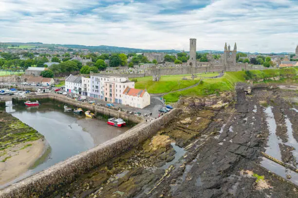 Drone view of St. Andrews, Fife Scotland with rocky coastline and village at low tide.