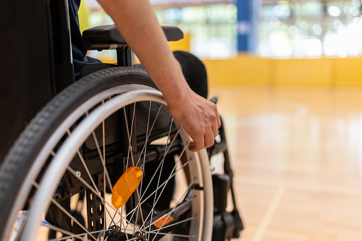 Disabled person with severe dystrophy in a wheelchair  in the gym on the floor.