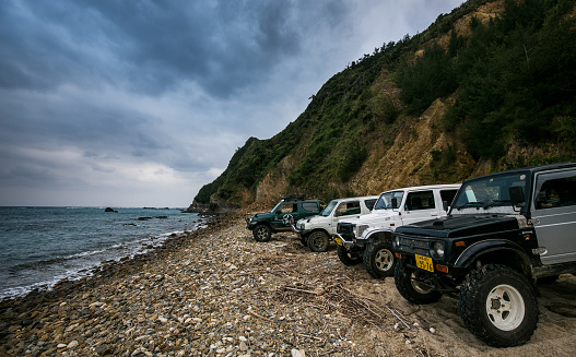 30th June 2023, Okinawa, Japan. A group of Suzuki Jimny enthusiasts park along a secluded beach to enjoy the ocean after a day of off road adventures.