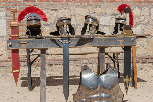 outdoor scene in horizontal view of an exhibitor with helmets, swords an cuirass of soldiers from the time of ancient roman empire. trip to the past