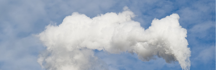 Flue chimney and smoke against blue sky UK