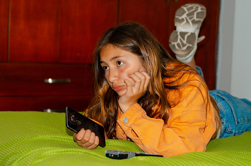 teen girl with smartphone lying in bed and copy space