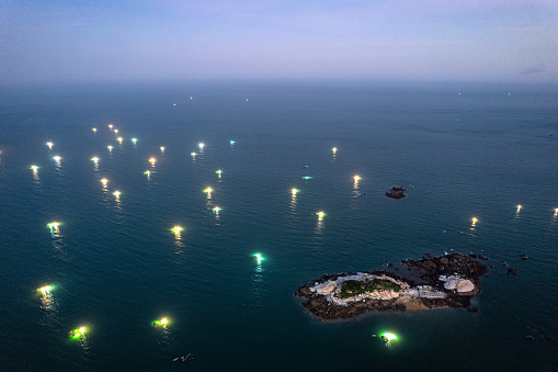 Town by the sea and many fishing boats with shining lights on the sea