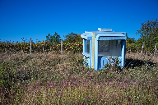 Light blue kiosk abandoned in a field