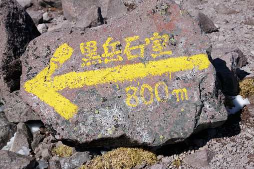 Yellow arrow hiking trail marker. Japanese text: Mt Kurodake refuge hut