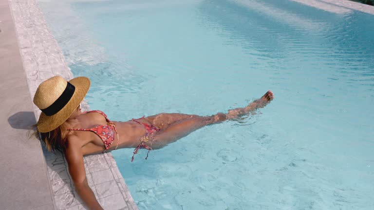 Lifestyle of woman relaxing at outdoor swimming pool.