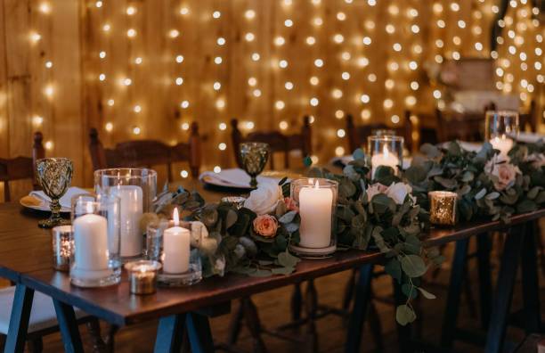 istock Rustic wooden table adorned with white candles and an arrangement of vibrant orange and white roses 1510287607