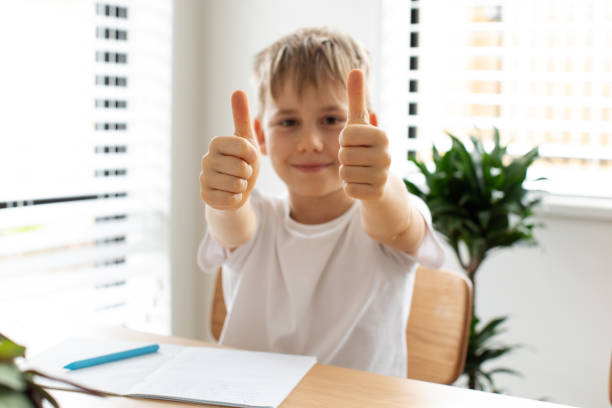 istock A smiling boy does his homework at the table and gives a thumbs up. Learning online education. 1510316755