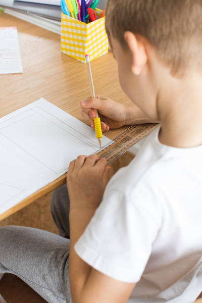 istock A cute boy makes a drawing with a ruler and pencil. Home lessons. Geometry and drawing. 1510322014