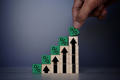 Hand placing wooden blocks with percentage sign and upward arrow. Interest rate, mortgage rates, financial growth, inflation, sale price and tax rise concept