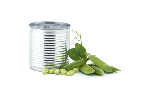 Tin can alongside fresh garden peas pods with green leaves isolated on a white background, sweet peas or English peas