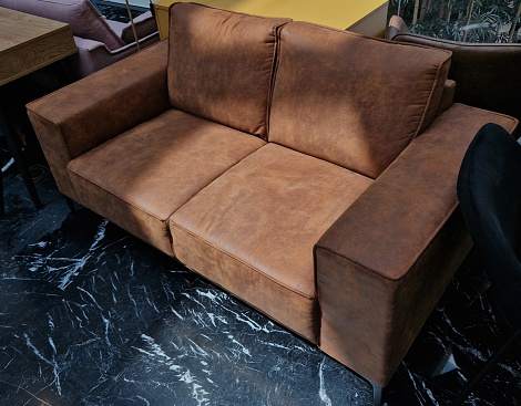 leather sofa with marble floor. brown color suede. luxurious lobby of the hotel. padded armchair for two people