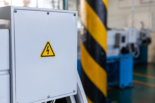 High voltage sign on machine at industrial plant. Occupational and safety caution sign for worker in factory concept.