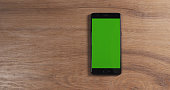 smartphone with green screen over wood table