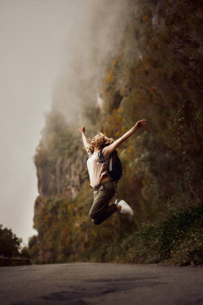 istock Playful female backpacker jumping on the road in nature. 1510550496