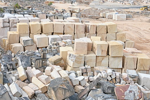 Wide angle view of an open cut sandstone quarry showing cut pieces of stone