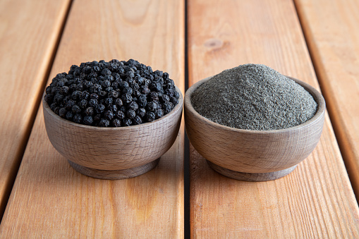 Ground black pepper with peppercorns  on a wooden table