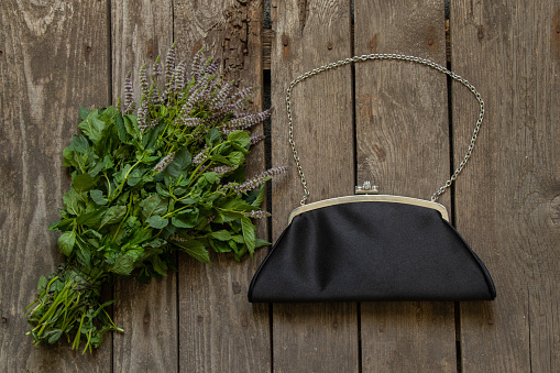 black black small bag and blooming mint on an wooden table