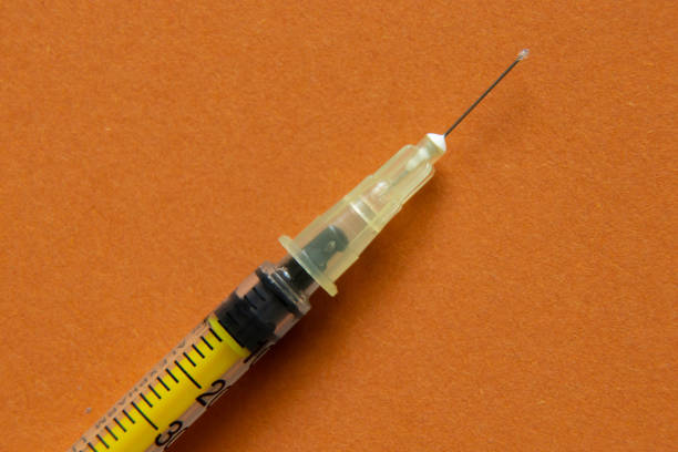 yellow empty syringe macro photo on orange background close up