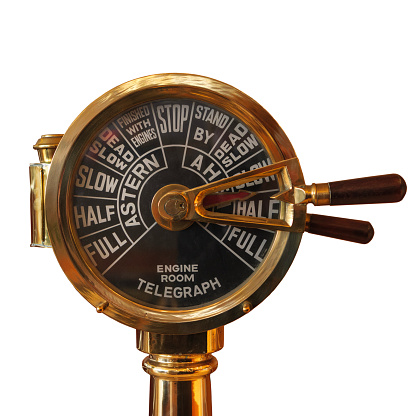 A brass ship telegraph indicating instructions to the engine room close up, isolated on white