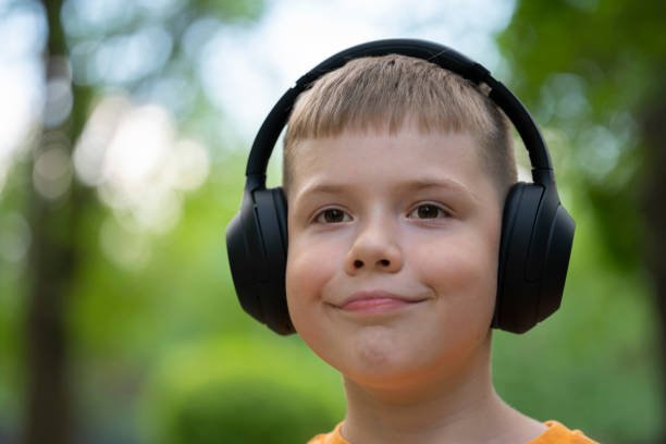 portret ośmioletniego blondyna ze słuchawkami bezprzewodowymi na głowie. koncepcja: melomaniak, słuchanie muzyki, słuchanie audiobooka, nauka języków obcych - 8 9 years audio zdjęcia i obrazy z banku zdjęć