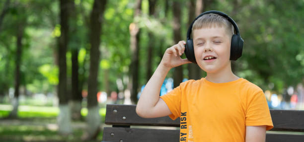 portret ośmioletniego blondyna ze słuchawkami bezprzewodowymi na głowie. koncepcja: melomaniak, słuchanie muzyki, słuchanie audiobooka, nauka języków obcych - 8 9 years audio zdjęcia i obrazy z banku zdjęć