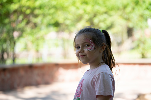 Summer portrait of a seven-year-old girl with a face painting.