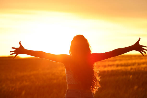 istock Female silhouette outstretching arms at sunset 1510672343