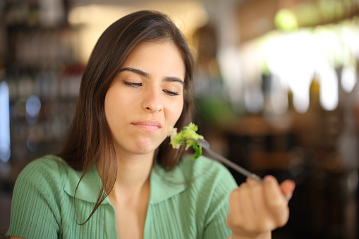 Disgusted woman eating lettuce in a restaurant