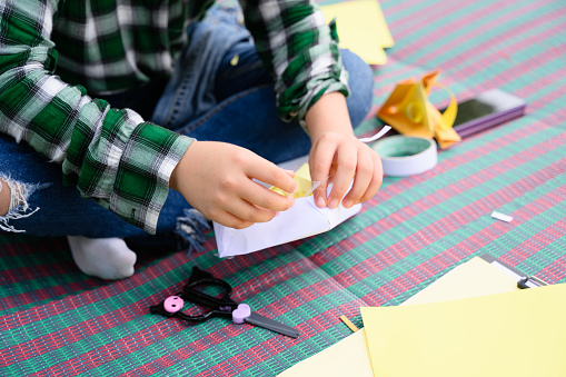 Happy girl making paper toy and playing in garden on weekend, Child with creative activities, Daughter playing toy on green field, Kid with leisure on free time