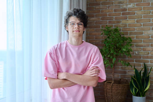 家のインテリアで腕を組んだ18、19歳のハンサムな男のポートレート - 20 25 years color image contemporary domestic life ストックフォトと画像