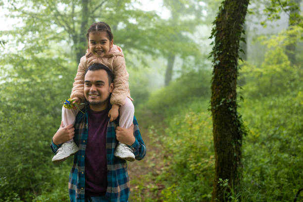 istock Father carrying his daughter on his shoulders while walking in a forest 1510732508
