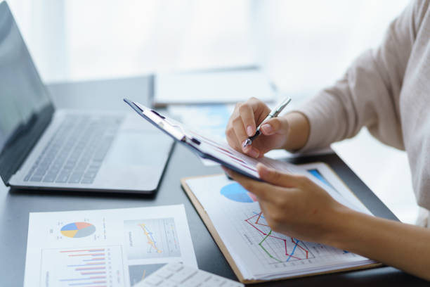 Close-up of a business woman analyzing charts and graphs for comparison each quarter, showing a change in market strategy. stock photo