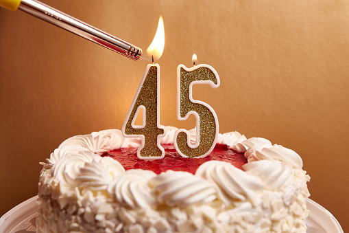 A candle in the form of the number 45, stuck in a festive cake, is lit. Celebrating a birthday or a landmark event. The climax of the celebration.