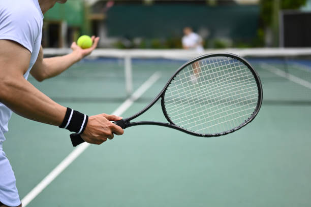 tennisspieler, der tennisball während eines spiels auf offenem platz serviert. sport-, trainings- und aktives lebenskonzept. - tennis court tennis ball racket stock-fotos und bilder