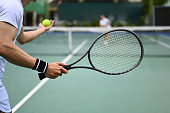 Tennis player serving tennis ball during a match on open court. Sport, training and active life concept.